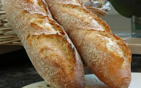 Zwei knusprige Baguettes, eine köstliche t65 Mehl Alternative, liegen auf einem Holzbrett.
