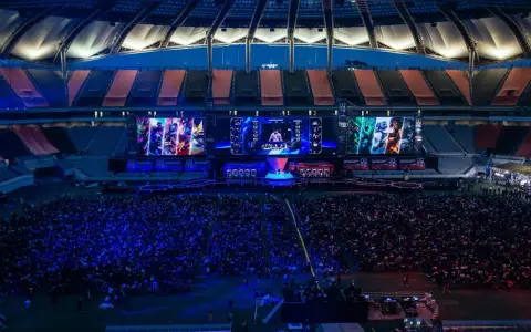 Wielki stadion wypełniony fanami oglądającymi transmisję z gry League of Legends. Na ekranach widać postacie i graczy, a tłum reaguje na emocjonujące rangi w lolu.