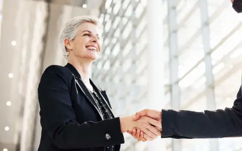 Due professionisti si stringono la mano, un gesto di accordo e fiducia. Sono colleghi raccomandati sul lavoro, pronti a collaborare.