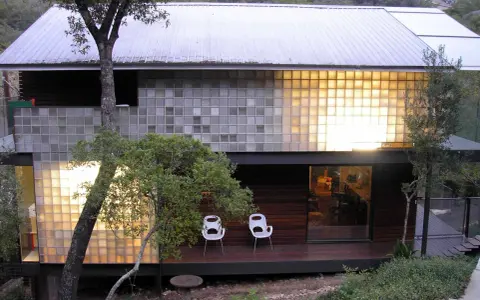 Modern house with a striking glass block installation, bathing the interior in warm light.