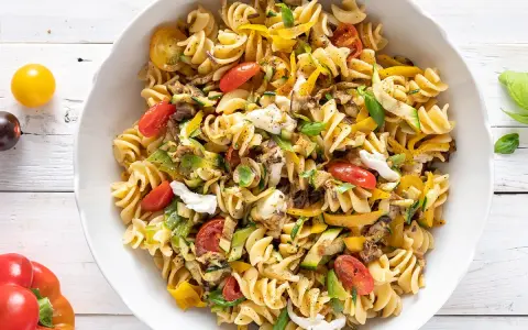 Un piatto colorato di pasta estiva veloce con fusilli, zucchine, peperoni gialli, pomodorini e mozzarella.