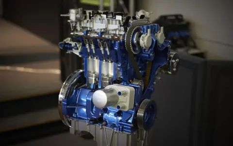 Przekrój silnika 1.0 Ecoboost w kolorze niebieskim, z widocznymi tłokami i paskiem rozrządu.
