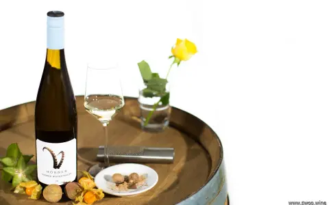 Flasche Gelber Muskateller Wein, Glas, Sternfrucht, Physalis, Litschi und Muskatnuss auf einem Holzfass.