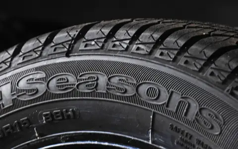 Bliżej opona z napisem "4Seasons", sugerująca najlepsze opony wielosezonowe. Bieżnik gotowy na każdą pogodę.