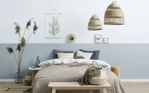 Sypialnia z łóżkiem i dwukolorową ścianą, pokazującą, jak połączyć dwa kolory na jednej ścianie. Wnętrze w stylu boho.