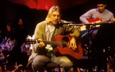 Kurt Cobain gra na gitarze akustycznej, czuć atmosferę, która pachnie nirvaną.