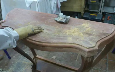 Proceso de como decapar un mueble antiguo, lijando la superficie para eliminar la pintura vieja.
