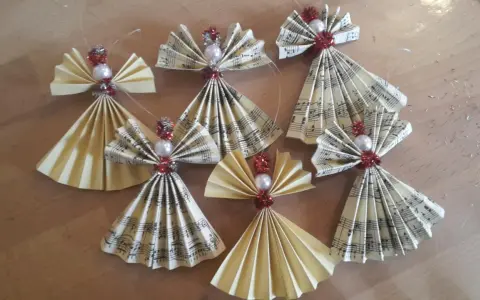 Selbstgemachter Christbaumschmuck: Kleine Weihnachtsengel aus Notenpapier und Perlen, die zum Basteln einladen.