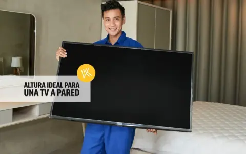 Hombre sonriente sostiene un televisor, listo para instalarlo. La altura ideal para un mueble de TV suspendido es clave.