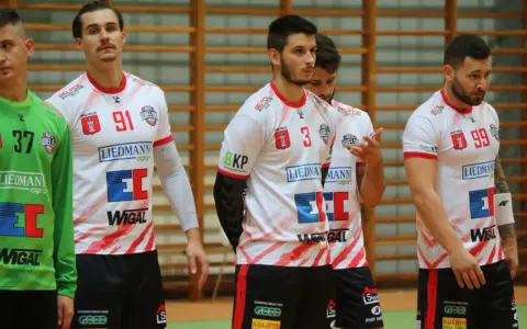 Szymon Kucharski i koledzy z drużyny w białych strojach z czerwonymi detalami, gotowi do gry.