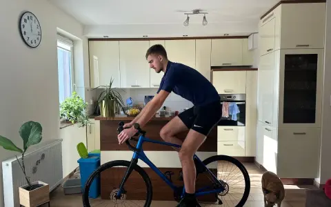 Mężczyzna w pozycji na rowerze gravel w kuchni, obok niego pies.
