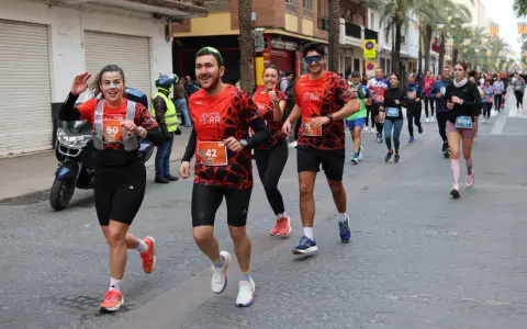 Corredores alegres participan en una media maratón, con dorsales visibles. El ambiente festivo sugiere un evento deportivo emocionante, parte de un calendario de medias maratones.