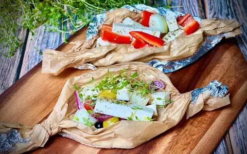 Zwei Päckchen mit Feta, Paprika, Zwiebeln und Kräutern warten darauf, gegrillt zu werden. Ein Genuss für den Gaumen!