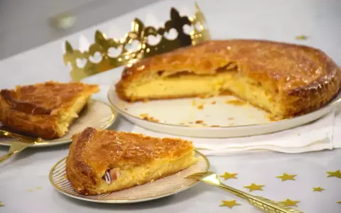 Une galette de farine dorée, prête à être dégustée, avec une fève cachée dans une part. Une couronne dorée trône à côté, promesse de fête.