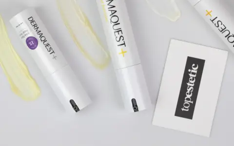 Kremy z retinolem, jak te z linii DERMAQUEST+, mogą powodować efekty uboczne. Na zdjęciu widać opakowania kosmetyków i próbki kremów.