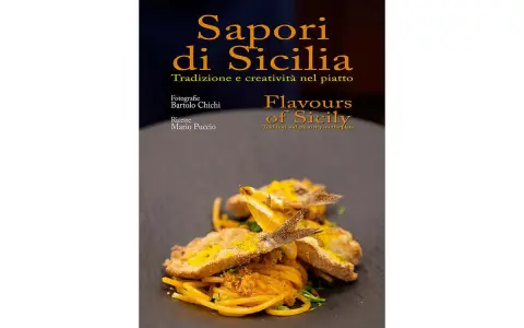 Un piatto di spaghetti con pesce fritto e scorza d'arancia, che celebra i sapori tipici siciliani.