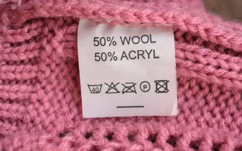 En rosa stickad tröja med en etikett som visar 50% ull och 50% akryl.