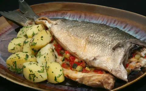 Lubina al horno con verduras y patatas. Un plato principal delicioso y saludable.