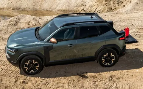 Zielony Dacia pickup z otwartą klapą bagażnika i czerwoną kanistrem na piasku.