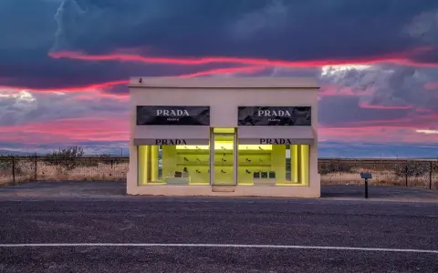 Prada Marfa, une installation artistique isolée au Texas, se dresse sous un ciel crépusculaire aux teintes roses et violettes.