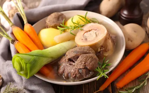 Un plat réconfortant de pot au feu, avec du bœuf, des carottes, des pommes de terre et des poireaux, garni de romarin.