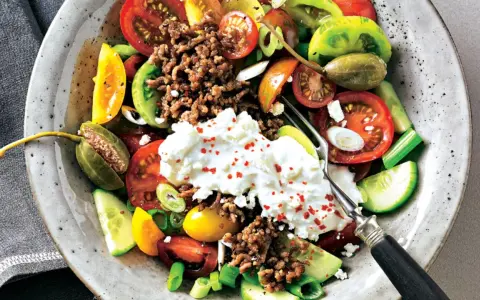 Bunter Tomatensalat mit Feta, Hackfleisch und Kapern. Frische Tomaten, Gurken und Frühlingszwiebeln bilden die Basis für diesen herzhaften Salat.
