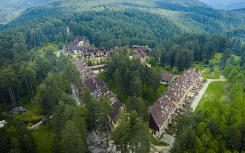 Villaggio Mancuso immerso nel verde, con case a schiera e palazzine circondate da fitti boschi di conifere.