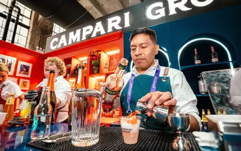 Barman nalewa Aperol do drinka, w tle logo Campari.