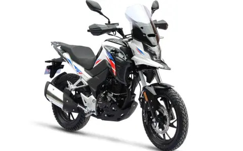 Nowy motocykl gotowy do docierania. Biało-czarny z czerwono-niebieskimi akcentami, z wysoką szybą i terenowymi oponami.