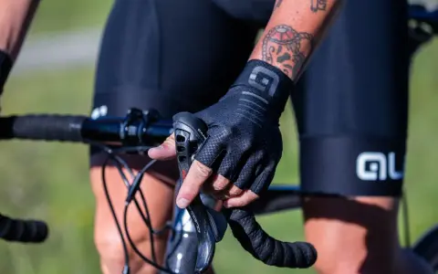 Rowerzysta w czarnych, bezpalczastych rękawiczkach, idealnych na rower, trzyma kierownicę.