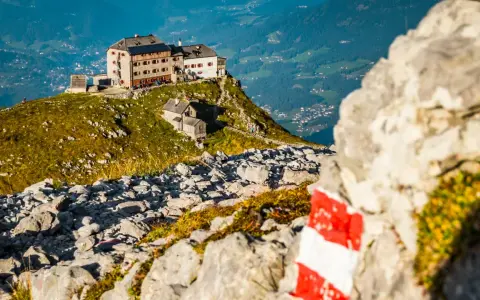 Watzmannhaus Wanderung: Ein markierter Weg führt zu diesem Berggasthof auf einem felsigen Grat mit Blick ins Tal.