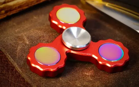 Röd fidget spinner med regnbågseffekter på de tre yttre delarna.