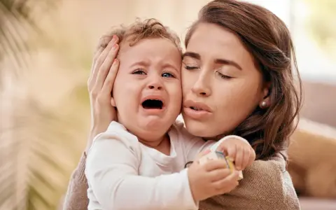 Zmartwiona mama tuli płaczące dziecko. Czy to mamoza?