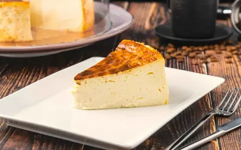 Rebanada de tarta italiana mascarpone con corteza dorada, servida en plato blanco con cubiertos.