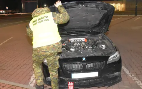 Funkcjonariusz Straży Granicznej sprawdza silnik BMW, wykonując rozkodowanie VIN.