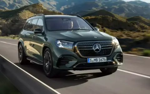 Zielony Mercedes GLS 580 pędzi po krętej drodze wśród gór.