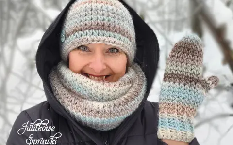 Uśmiechnięta kobieta w zimowym otoczeniu prezentuje ręcznie robione wzory czapek na szydełku i rękawiczki.