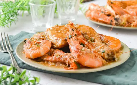 Plato de pollo con gambas en salsa, decorado con perejil picado. Se ve delicioso y listo para disfrutar.