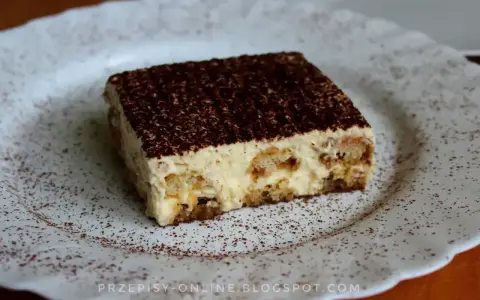 Pyszne tiramisu, czyli zabajone, na białym talerzu, posypane kakao.