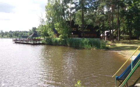 Malownicze łowisko Baroniok nad jeziorem, z drewnianym pomostem, domkami i zjeżdżalnią.