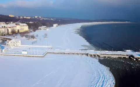 Zimowy spacer po molo w Sopocie to świetny pomysł, gdzie na ferie zimowe. Wokół biała, śnieżna przestrzeń i błękitne niebo.