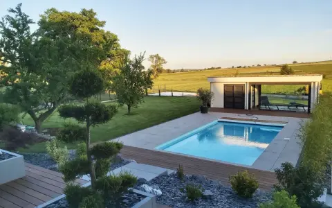 Magnifique jardin avec piscine, pelouse impeccable, arbres taillés et une petite maison moderne. Un havre de paix.
