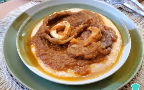 Un plato de osobuco de ternera cocinado a fuego lento, servido sobre una cama cremosa de polenta.
