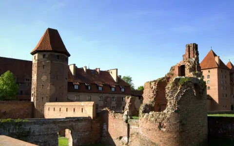 Potężne zamki nad morzem bałtyckim, w tym ruiny i zachowane budowle z cegły, pod błękitnym niebem.