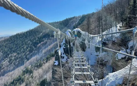 Zimowa przygoda na wiszącym moście nad przepaścią. Skalka pri Kremnici w śnieżnej odsłonie, z widokiem na zalesione zbocza.