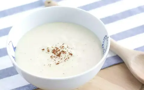 Un bol de sauce béchamel onctueuse, saupoudrée de noix de muscade râpée, prêt pour votre recette.