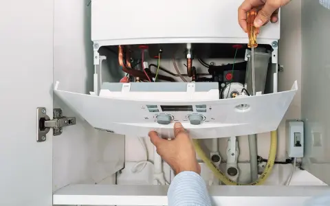 Hände reparieren einen Thermoflow Durchlauferhitzer. Eine Anleitung wird befolgt, um die Komponenten zu überprüfen.