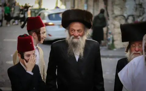 Men in traditional attire, including fur hats and red fez hats, walk together, perhaps celebrating the Purim meaning of joy and community.