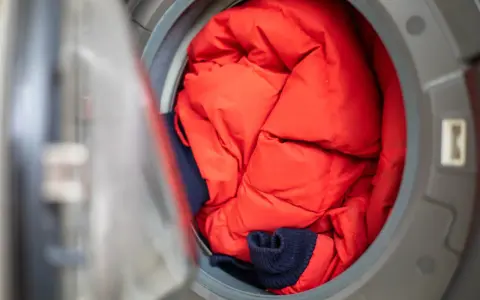 Czerwona kurtka puchowa i granatowy sweter czekają na program outdoor w pralce, by znów być gotowe na przygody.