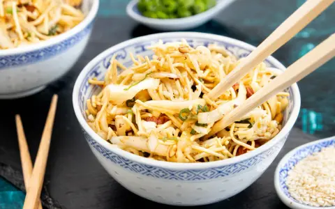 Friss dich dumm Salat: Nudeln, Gemüse und Nüsse in einer Schüssel, bereit zum Genießen mit Stäbchen.